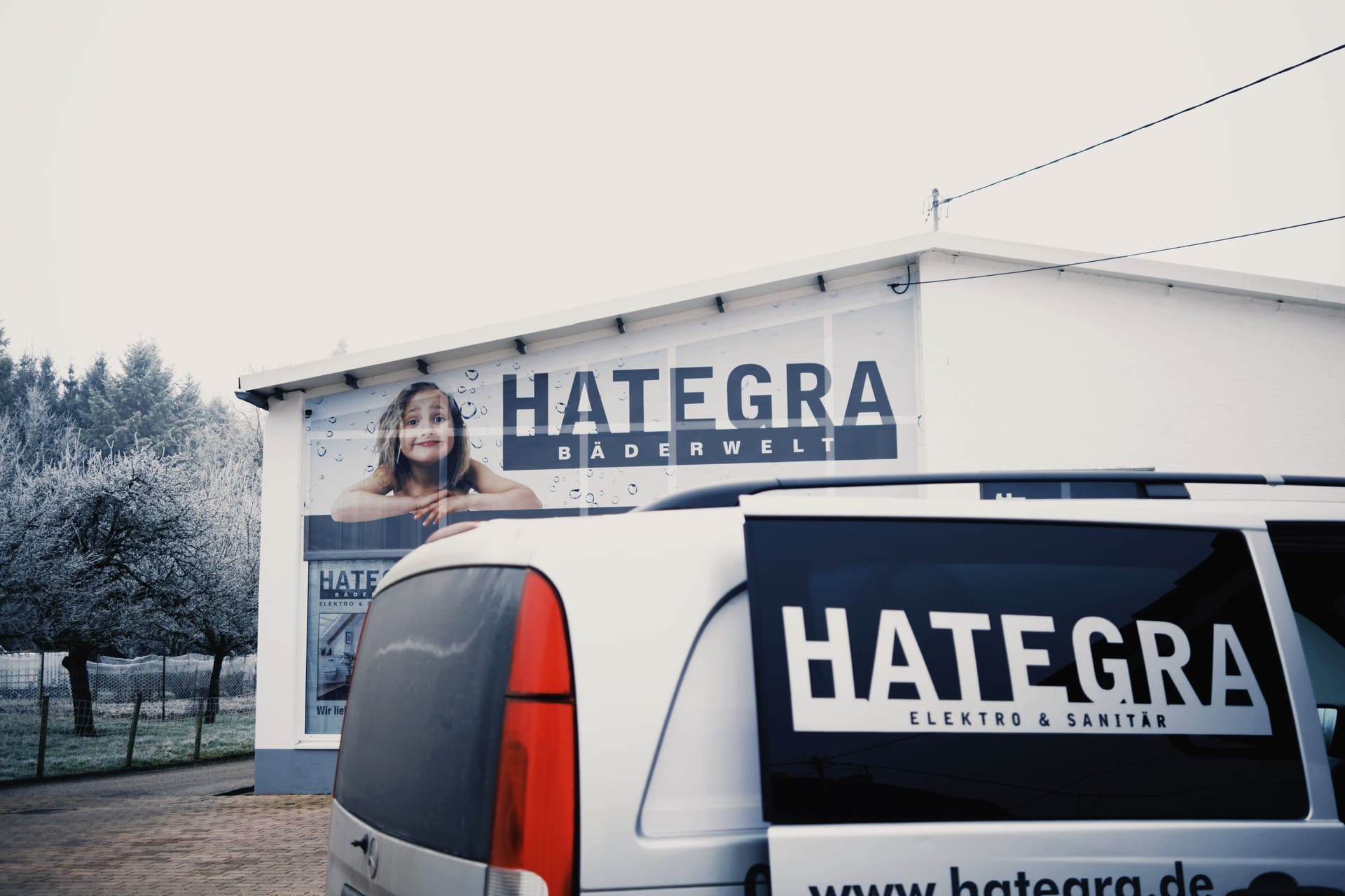 HATEGRA Bäderwelt Gebäude mit Firmenfahrzeug – Elektro und Sanitär Handwerksbetrieb